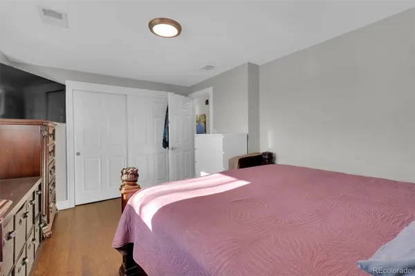 a bedroom with a bed dresser and a flat tv screen