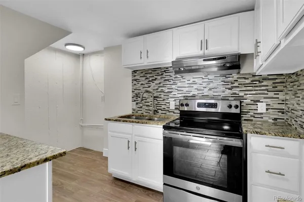 a kitchen with granite countertop white cabinets and stainless steel appliances