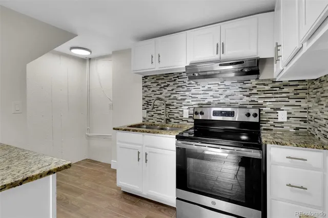 a kitchen with granite countertop white cabinets and stainless steel appliances