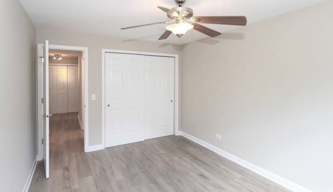 677 South River Road, Unit 2H Des Plaines, IL 60016 - Photo 8 of 15 an empty room with wooden floor fan and windows