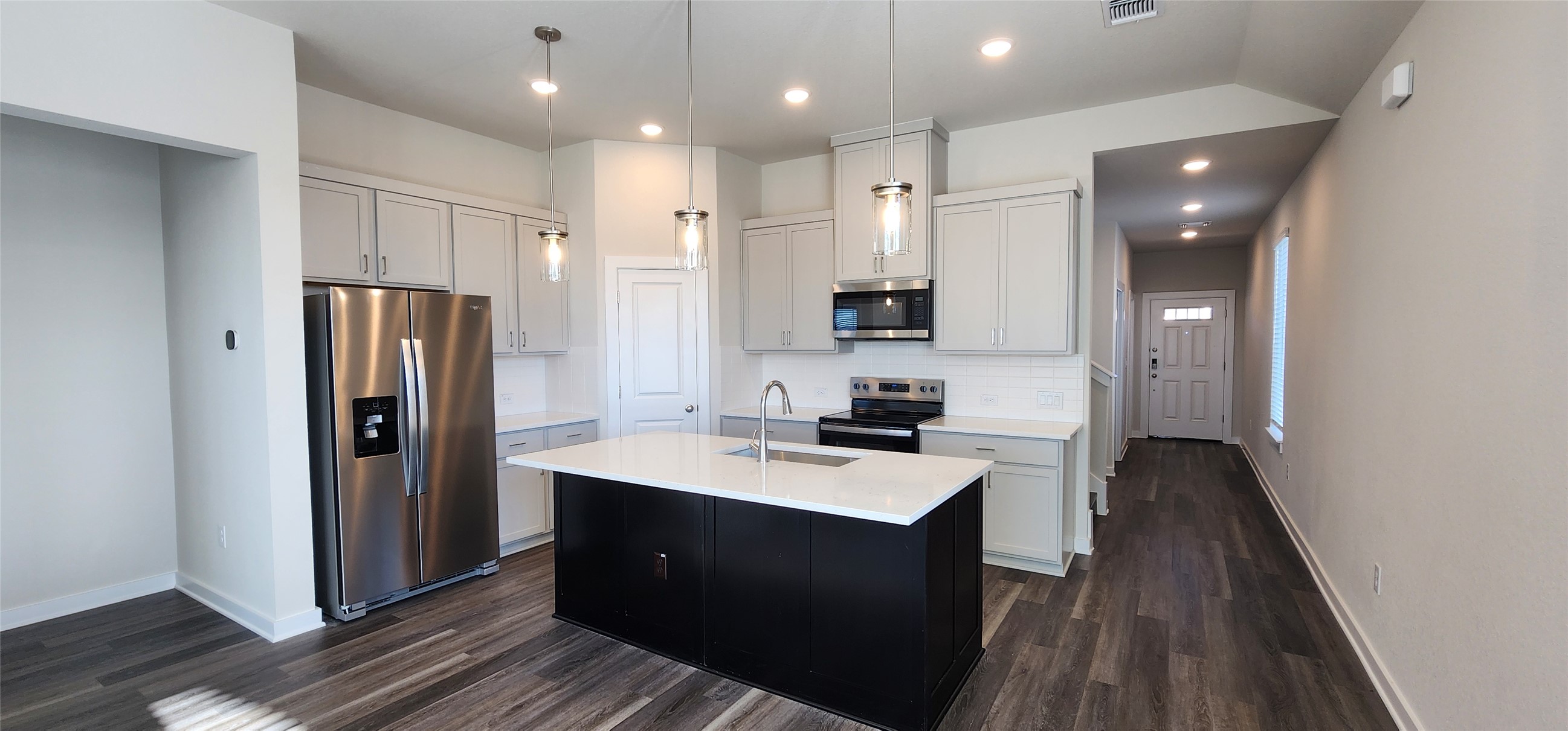 2248 Delano Drive Leander, TX 78641 - Photo 6 of 33 Kitchen with appliances with stainless steel finishes, an island with sink, dark wood finished floors, pendant lighting, and tasteful backsplash