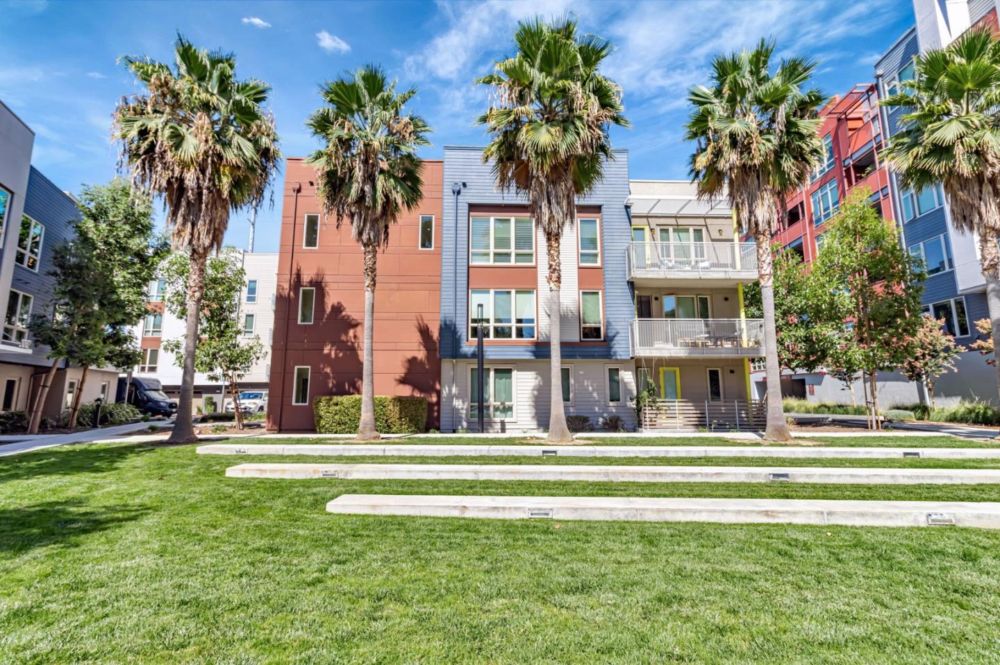 a front view of a residential apartment building with a garden and trees