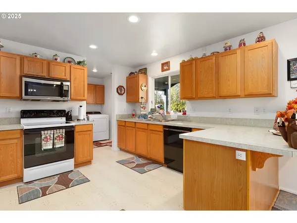 a kitchen with stainless steel appliances a sink a stove a microwave a sink a refrigerator and cabinets