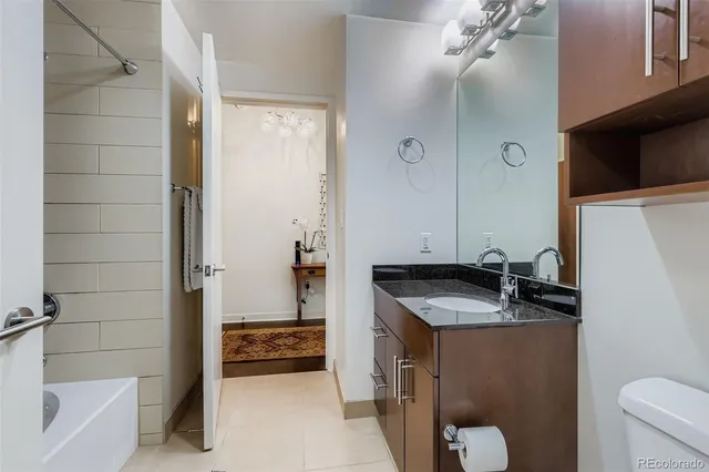 a bathroom with a granite countertop sink a toilet a mirror and bathtub