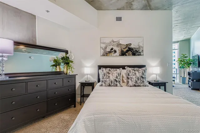 a bedroom with a large bed and a potted plant