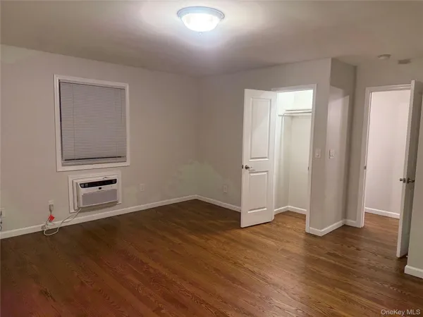 an empty room with wooden floor closet and windows