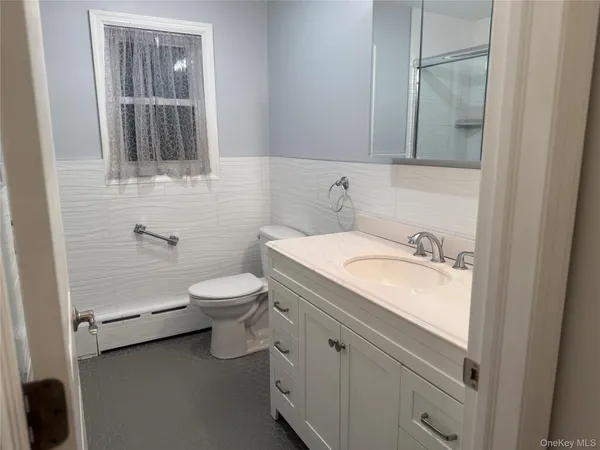 a bathroom with a granite countertop toilet sink and mirror