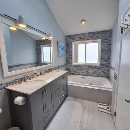 a spacious bathroom with a double vanity sink bathtub and a mirror