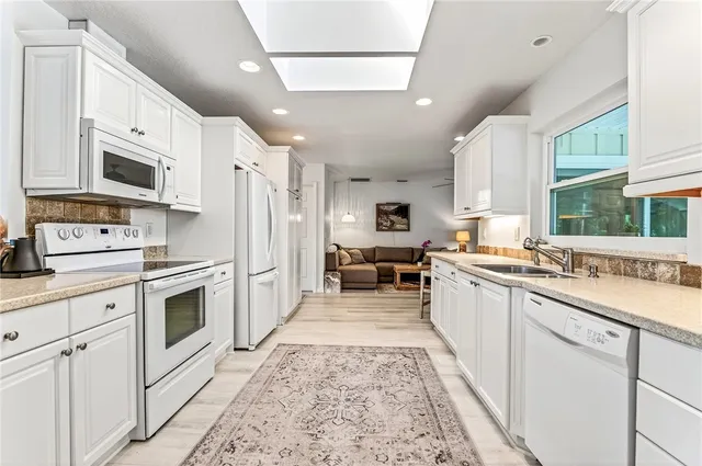 a large white kitchen with stainless steel appliances granite countertop a stove a sink dishwasher and a refrigerator