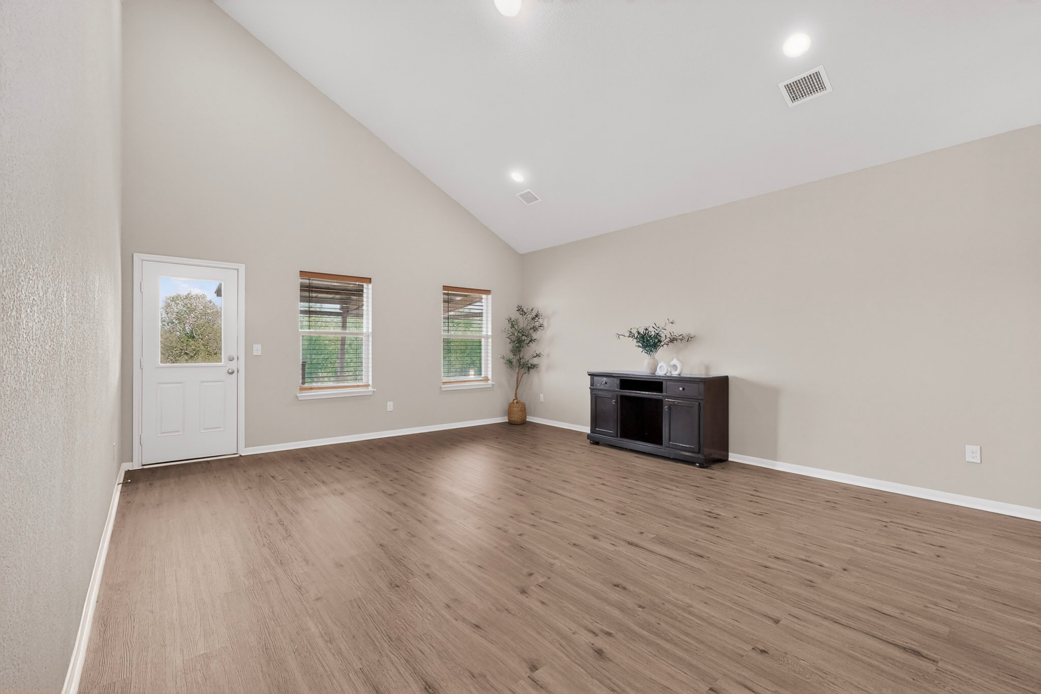 5905 Diamondleaf Bend Austin, TX 78724 - Photo 9 of 38 Vaulted ceiling living area featuring wood-finish flooring, recessed lighting, and multiple windows