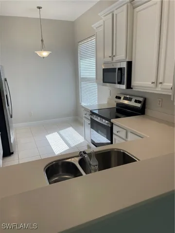 a kitchen with stainless steel appliances a white stove top oven a sink a microwave and a refrigerator