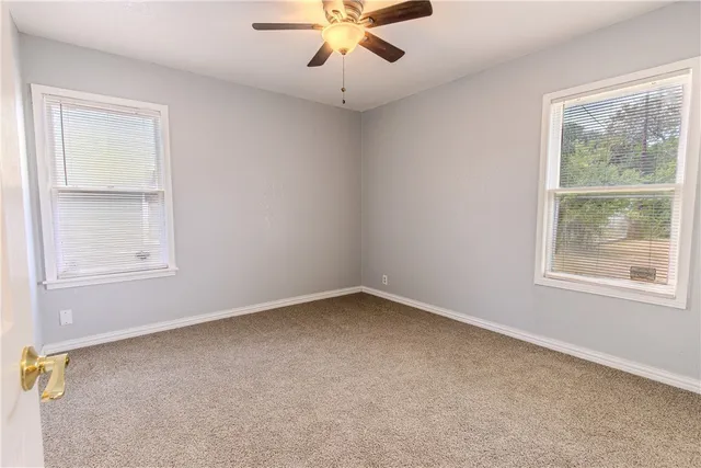 an empty room with a window and a fan