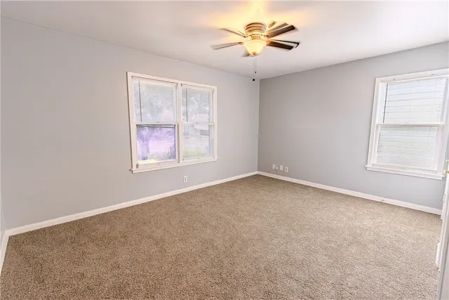 an empty room with windows and a chandelier fan