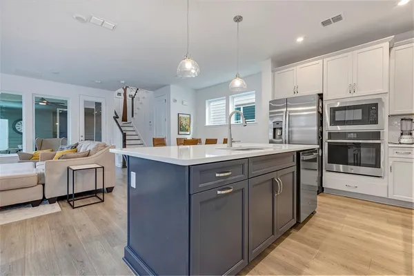 a kitchen with kitchen island granite countertop a sink cabinets and stainless steel appliances