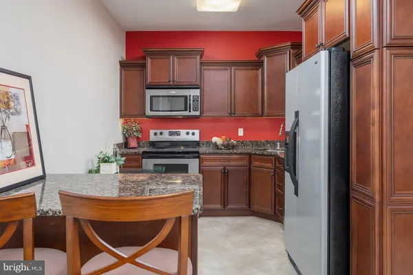 a kitchen with stainless steel appliances kitchen island granite countertop a refrigerator and a stove top oven