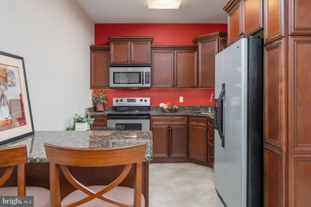 a kitchen with stainless steel appliances kitchen island granite countertop a refrigerator and a stove top oven