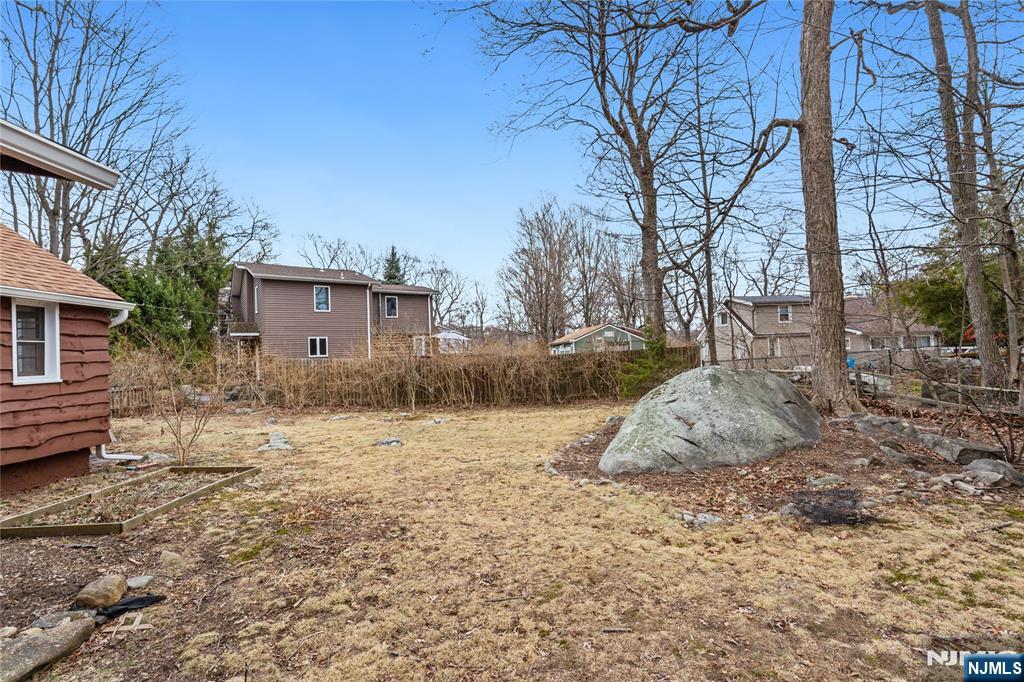 6 Partridge Trail Butler, NJ 07405 - Photo 35 of 37 a backyard of a house with large trees and wooden fence
