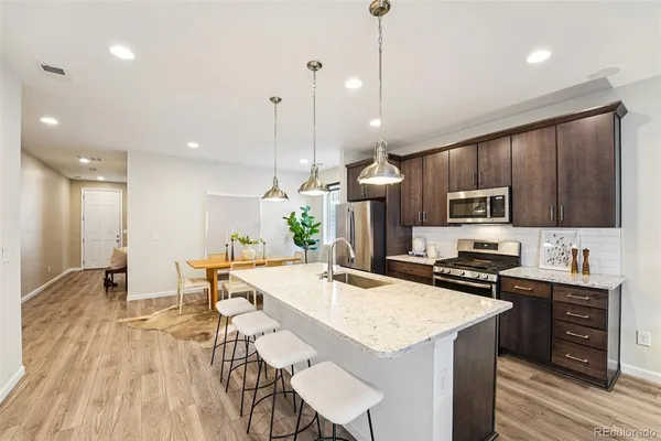 a kitchen with stainless steel appliances kitchen island granite countertop a sink a stove a refrigerator and island with wooden floor