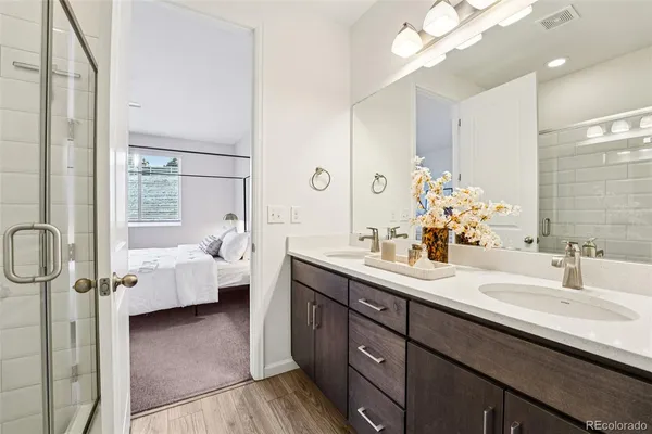 a en suite bathroom with a double vanity sink a large mirror and a shower