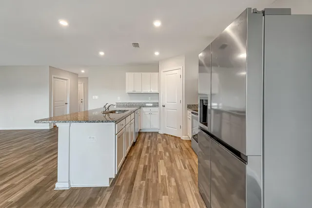 a large kitchen with a center island wooden floor stainless steel appliances and cabinets