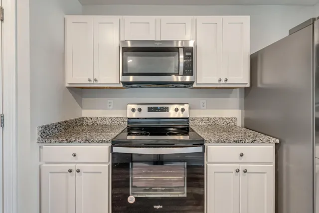 a kitchen with granite countertop white cabinets and stainless steel appliances
