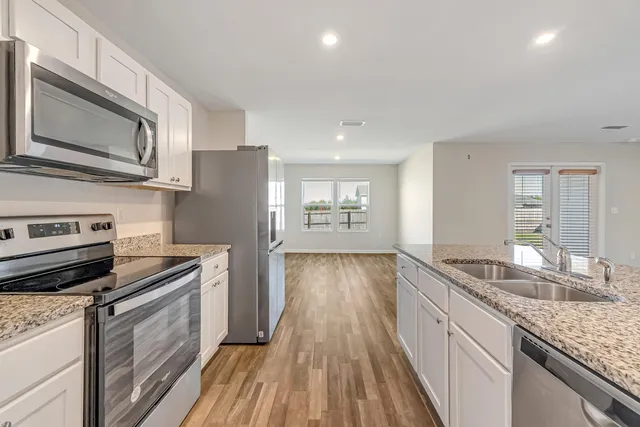 a kitchen with granite countertop a sink stove and refrigerator