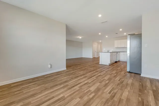a view of a big room with wooden floor and a kitchen