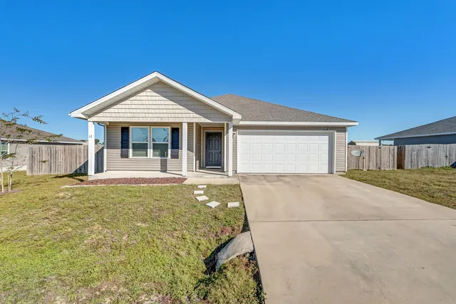 a view of a house with floor to ceiling windows and wooden fence