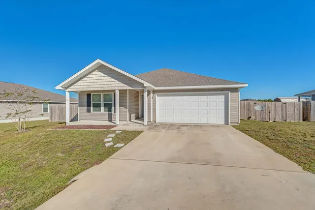 a front view of a house with a yard garage and wooden fence