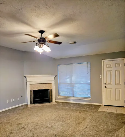 a view of an empty room with chandelier fan and fire place