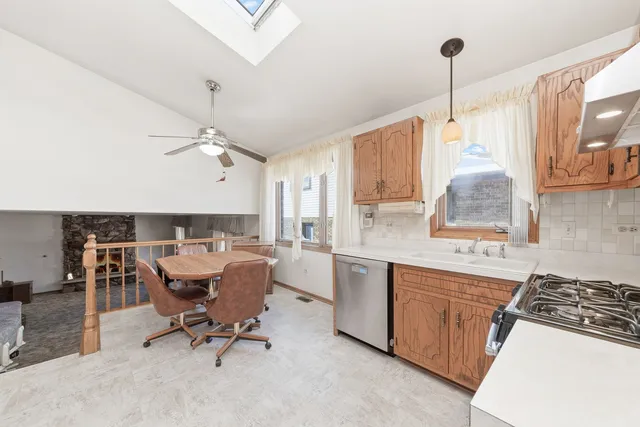 a open kitchen with stainless steel appliances granite countertop a stove top oven a sink dishwasher and white cabinets with wooden floor