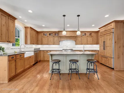 a kitchen with kitchen island granite countertop wooden floors and white cabinets