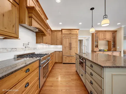 a large kitchen with stainless steel appliances granite countertop a lot of counter space and a sink