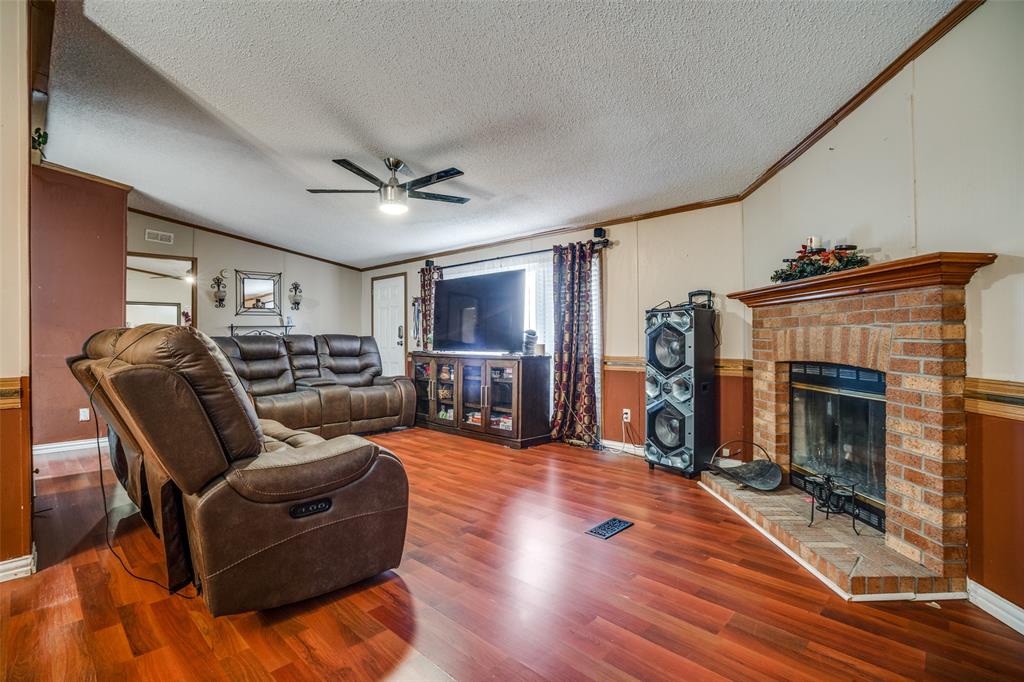 458 County Road 2131 Valley View, TX 76272 - Photo 4 of 13 Living room viewed from an alternate angle, highlighting the doorway to the primary bedroom and showcasing the spacious layout with ample room between seating areas
