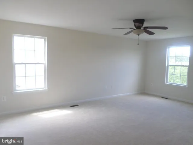 an empty room with a window and a fan