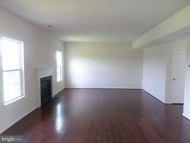 an empty room with wooden floor fireplace and windows