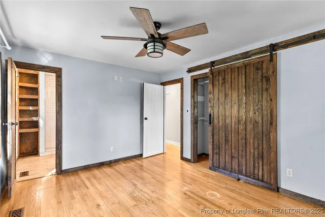 a view of an empty room with wooden floor and a ceiling fan