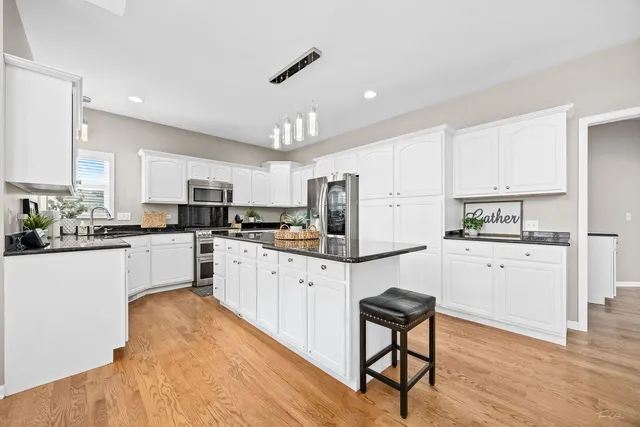 a kitchen with stainless steel appliances granite countertop a stove top oven a sink a counter space and cabinets