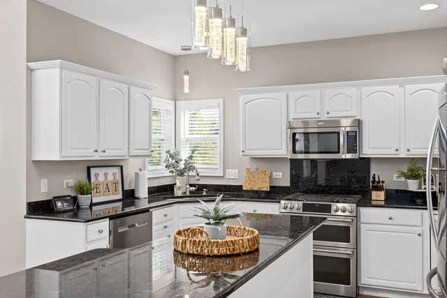 a kitchen with granite countertop a sink stainless steel appliances and white cabinets