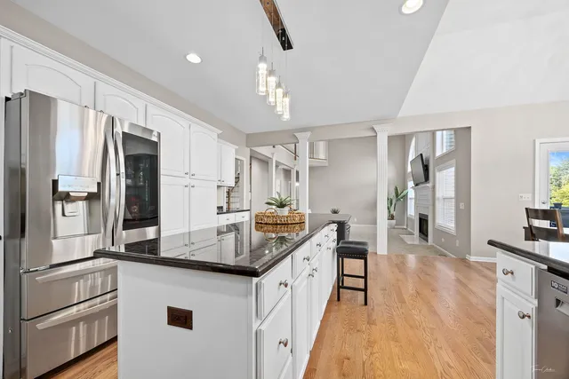 a kitchen with stainless steel appliances a table chairs refrigerator and cabinets