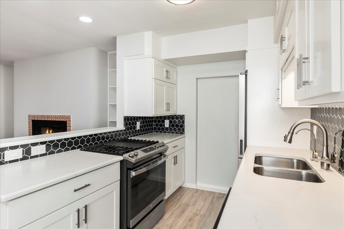 505 West 7th Street, Unit 313 Austin, TX 78701 - Photo 8 of 30 Kitchen featuring stainless steel range with gas cooktop, a sink, light wood-style flooring, backsplash, and white cabinetry