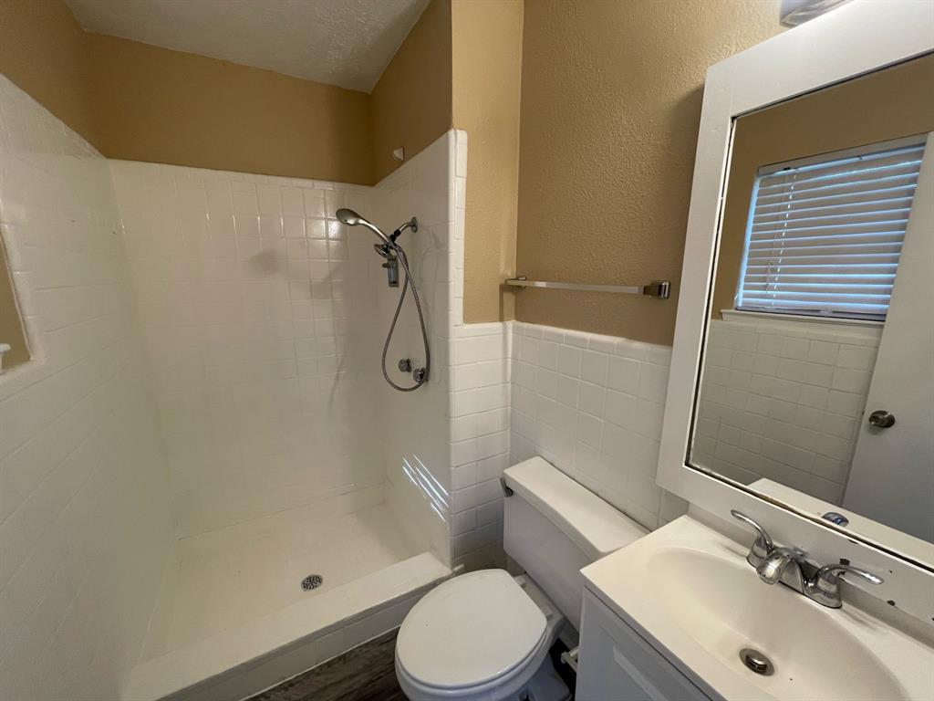 2310 Gilbert Circle Arlington, TX 76010 - Photo 6 of 9 Bathroom featuring vanity, toilet, tile walls, and a tile shower