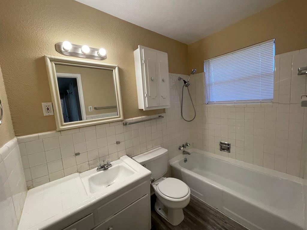2310 Gilbert Circle Arlington, TX 76010 - Photo 8 of 9 Full bathroom featuring hardwood / wood-style floors, toilet, vanity, tile walls, and tiled shower / bath