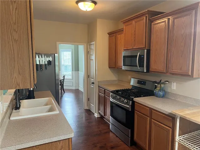 a kitchen with stainless steel appliances a stove a sink dishwasher a microwave oven and a refrigerator with wooden floor