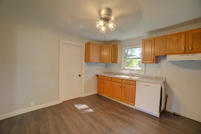 a kitchen with granite countertop white cabinets a sink a window and stainless steel appliances