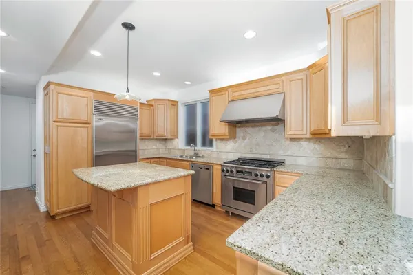 a kitchen with stainless steel appliances granite countertop a sink a stove and a refrigerator