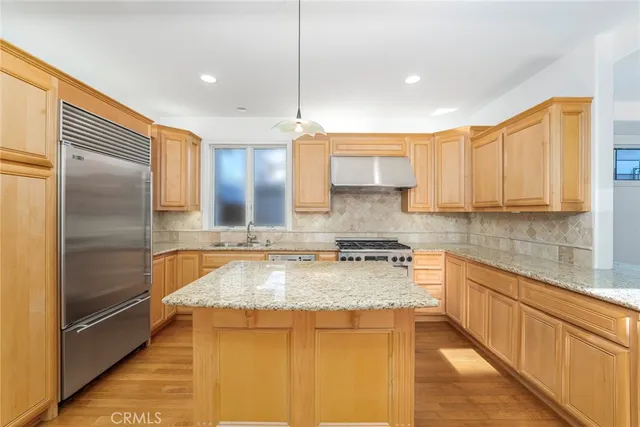 a kitchen with stainless steel appliances granite countertop a sink a stove and a refrigerator
