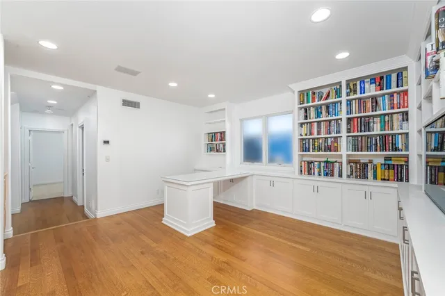 a view of an empty room with bookshelf and wooden floor