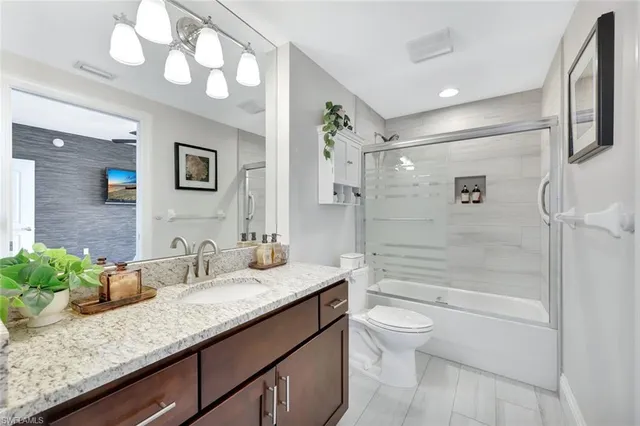 a bathroom with a granite countertop sink a toilet and shower