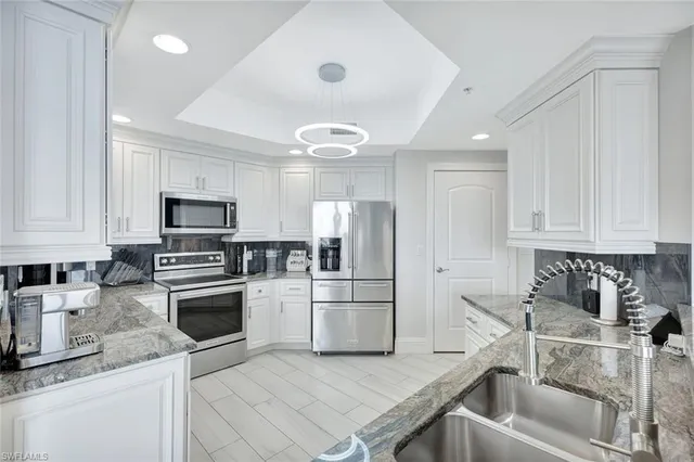 a kitchen with stainless steel appliances granite countertop a refrigerator a stove and a sink